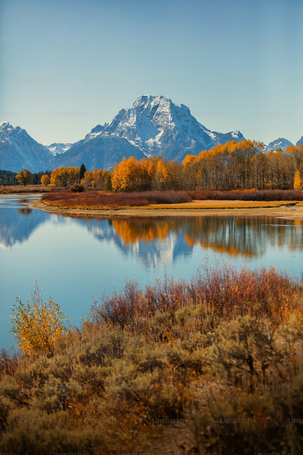 a lake surrounded by tall mountains with trees in the foreground