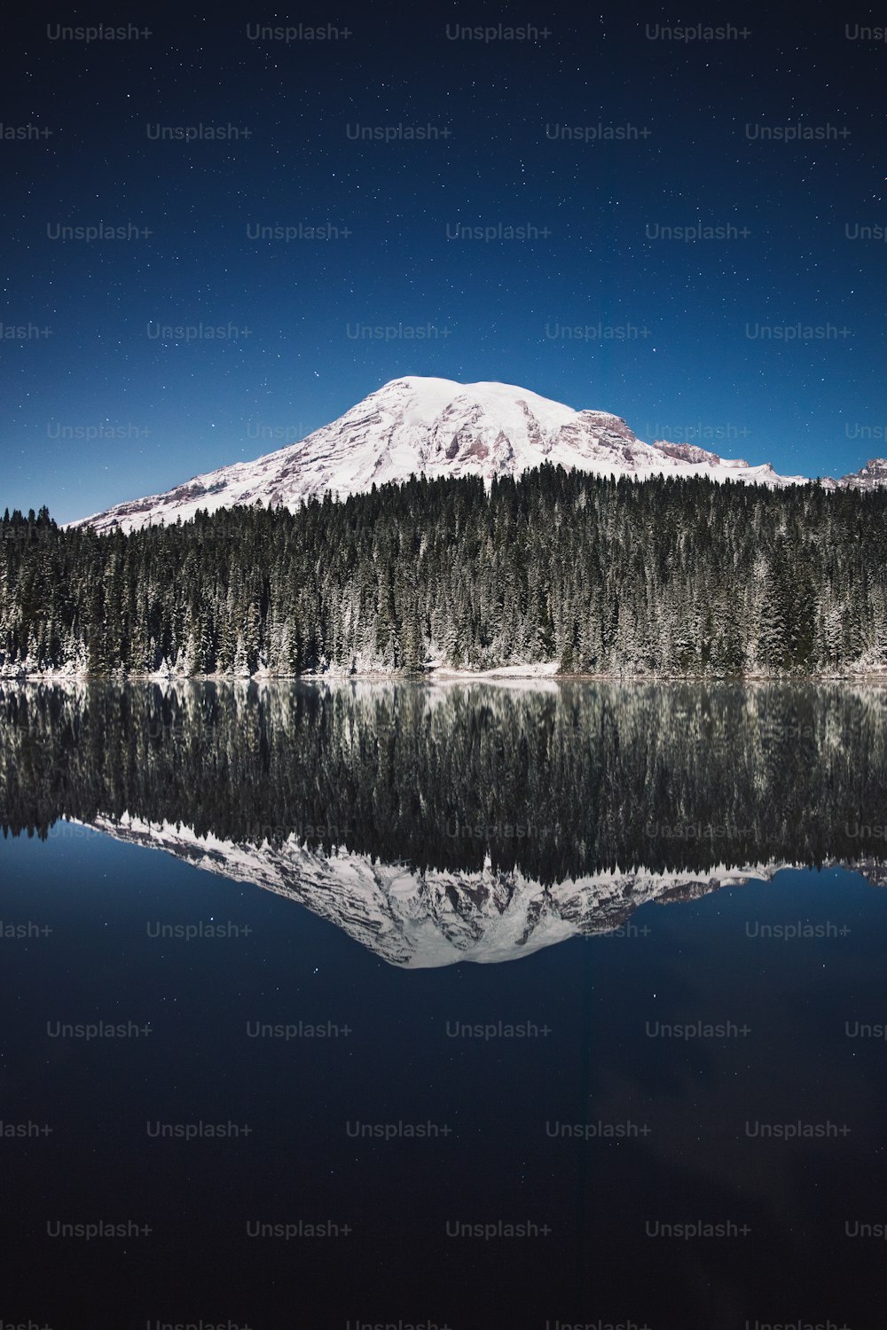 눈 덮인 산이 호수의 잔잔한 물에 반사되어