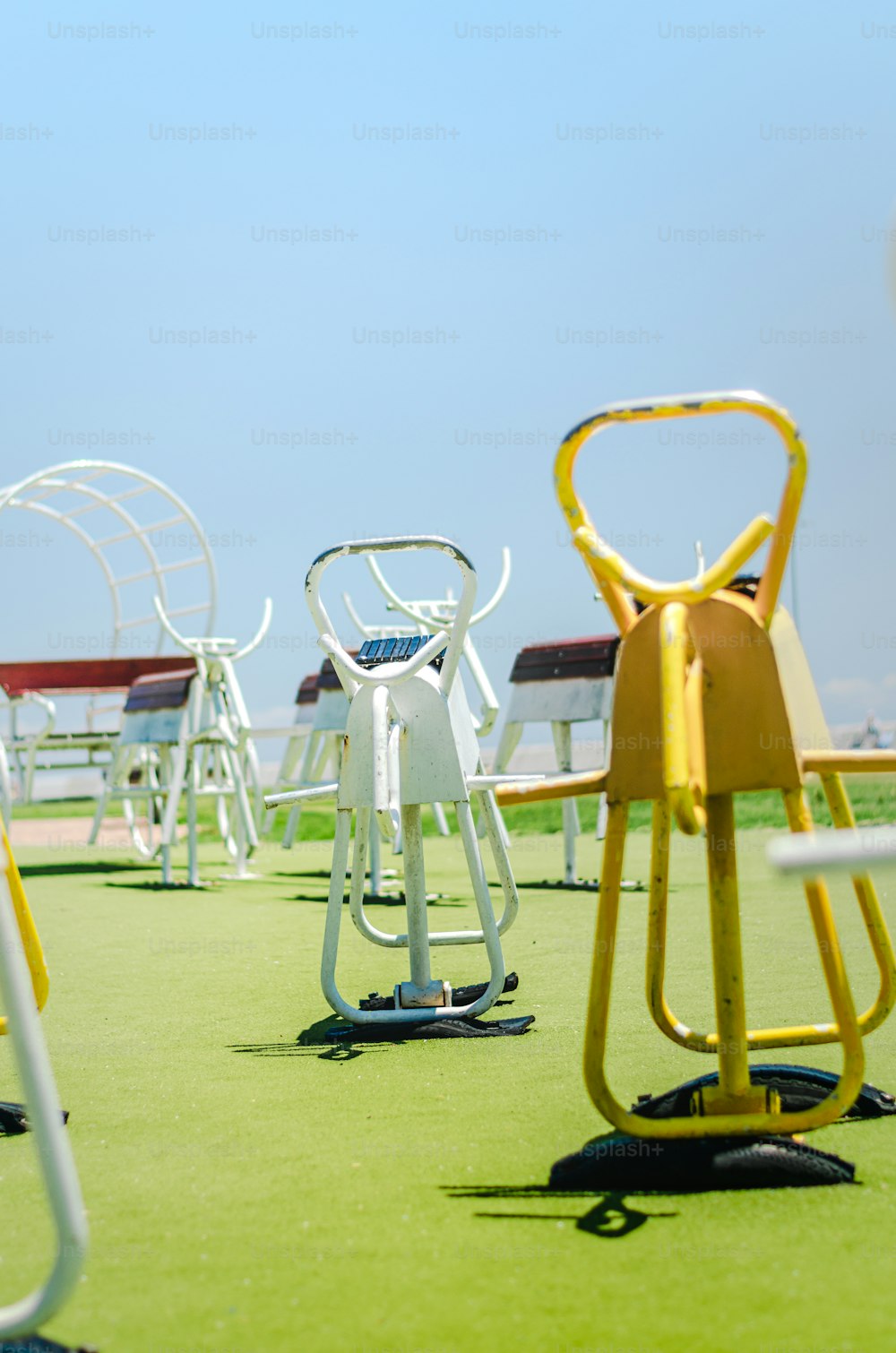 une rangée de chaises jaunes et blanches assises au sommet d’un champ vert