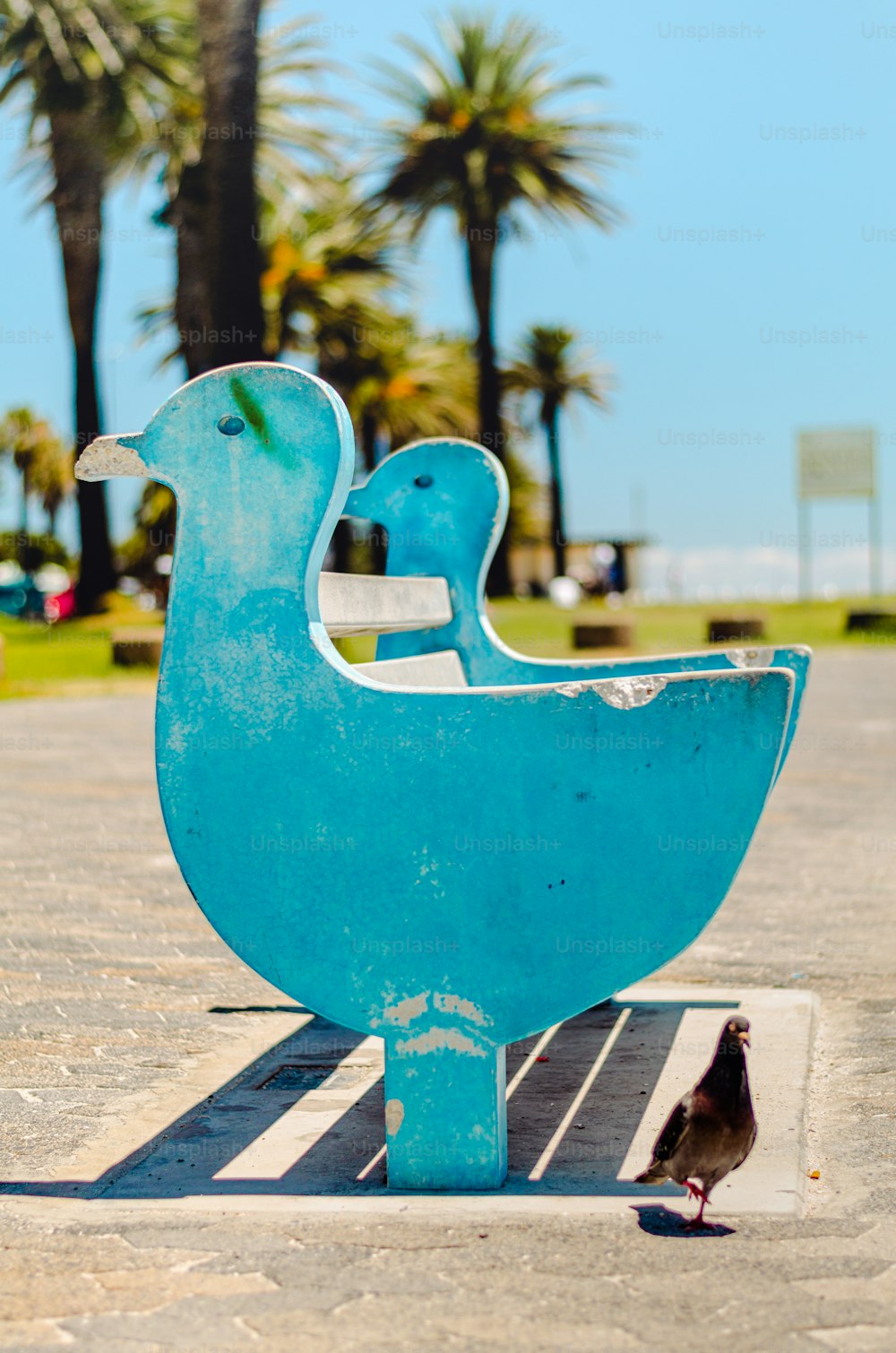 Ein kleiner Vogel steht neben einer blauen Skulptur