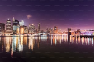 a city skyline at night with a bridge in the foreground