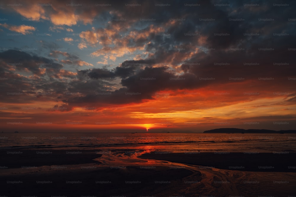 the sun is setting over the ocean on a cloudy day