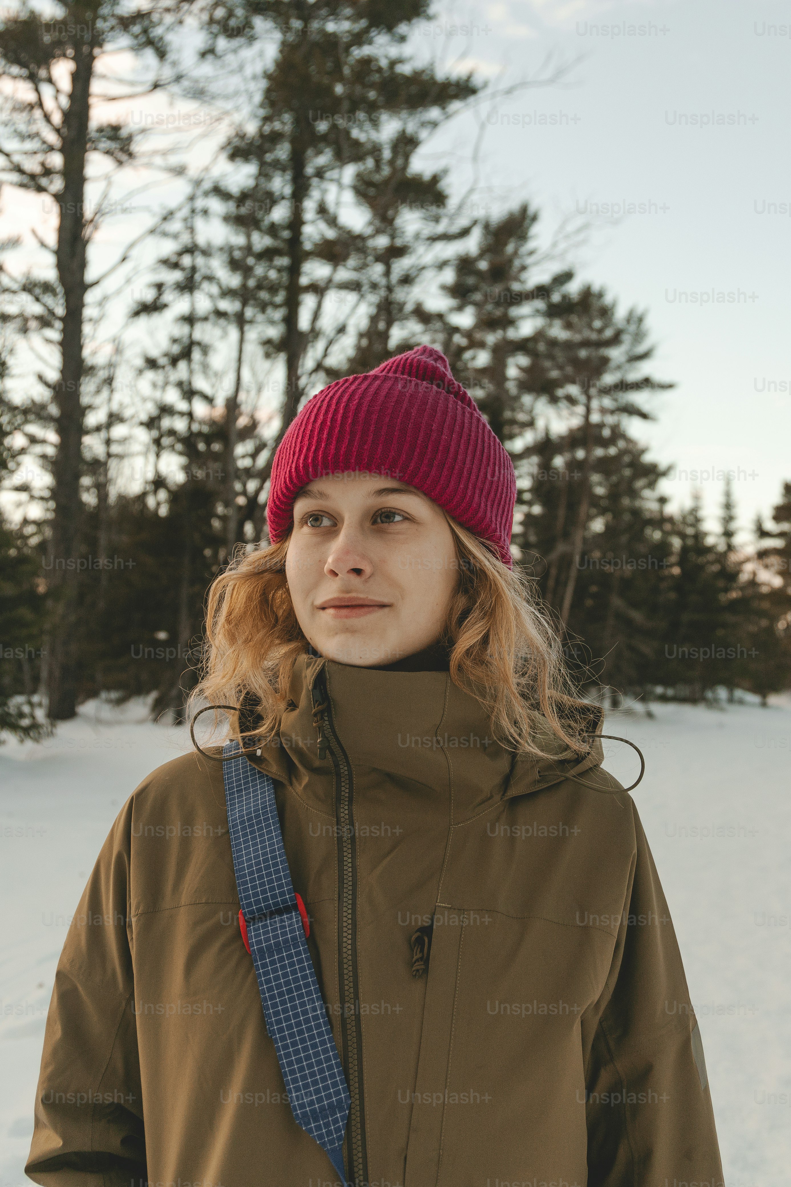 a woman standing in the snow wearing a red hat