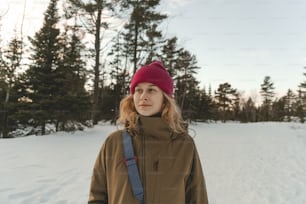 a woman standing in the snow wearing a red hat