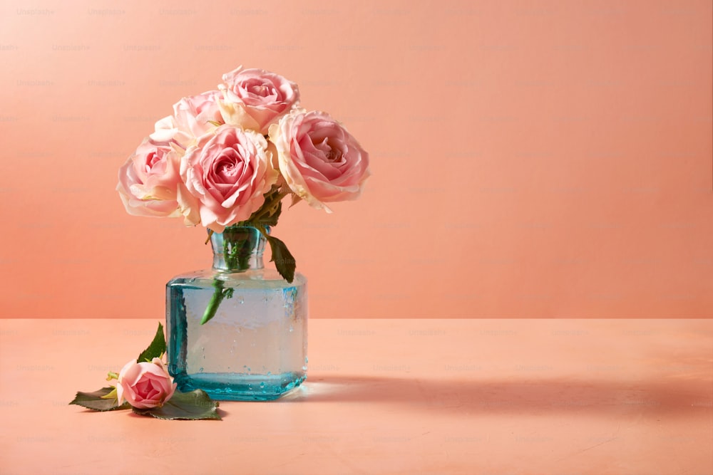 テーブルの上にあるピンクのバラでいっぱいの花瓶