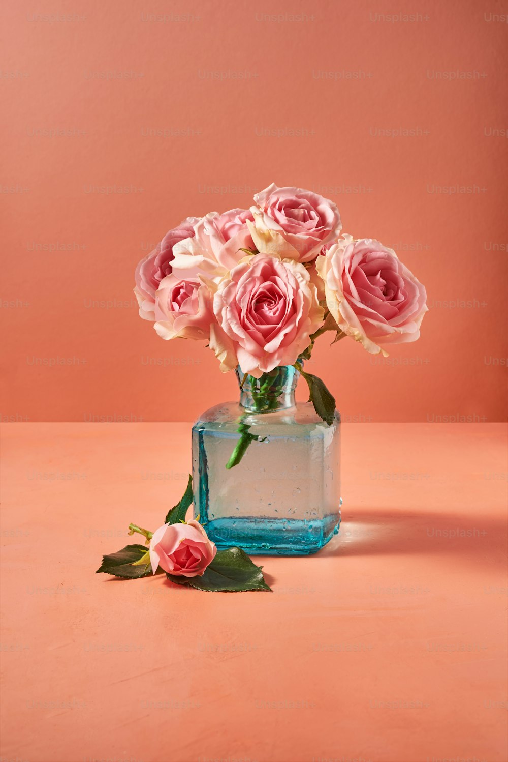 テーブルの上にあるピンクのバラでいっぱいの花瓶