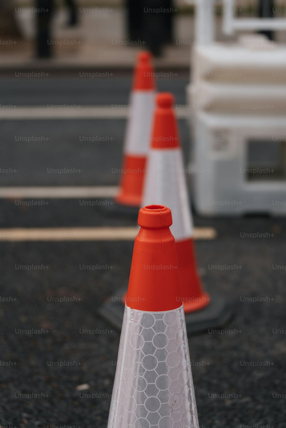 una fila di coni arancioni e bianchi seduti sul lato di una strada