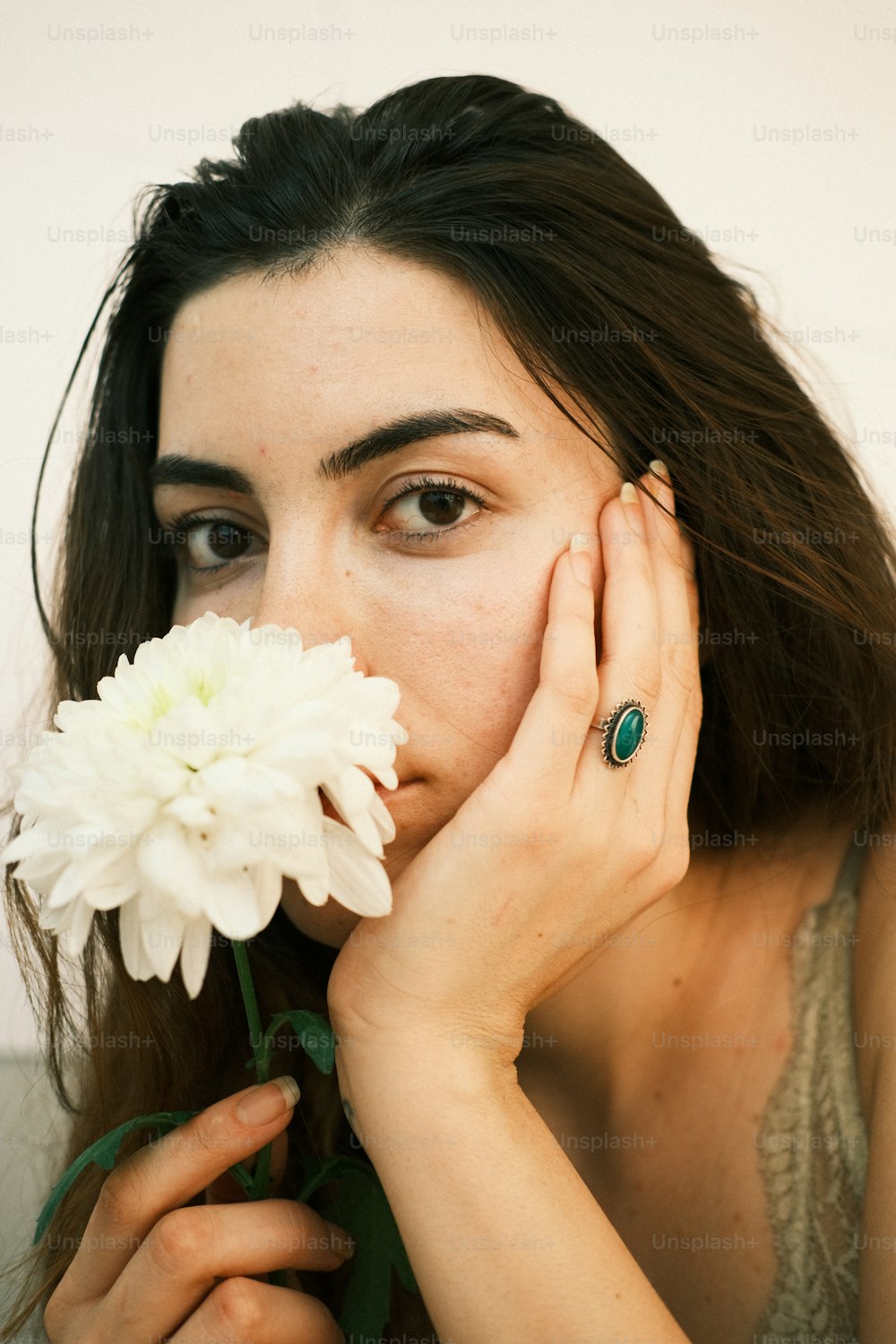 Una mujer sosteniendo una flor frente a su cara