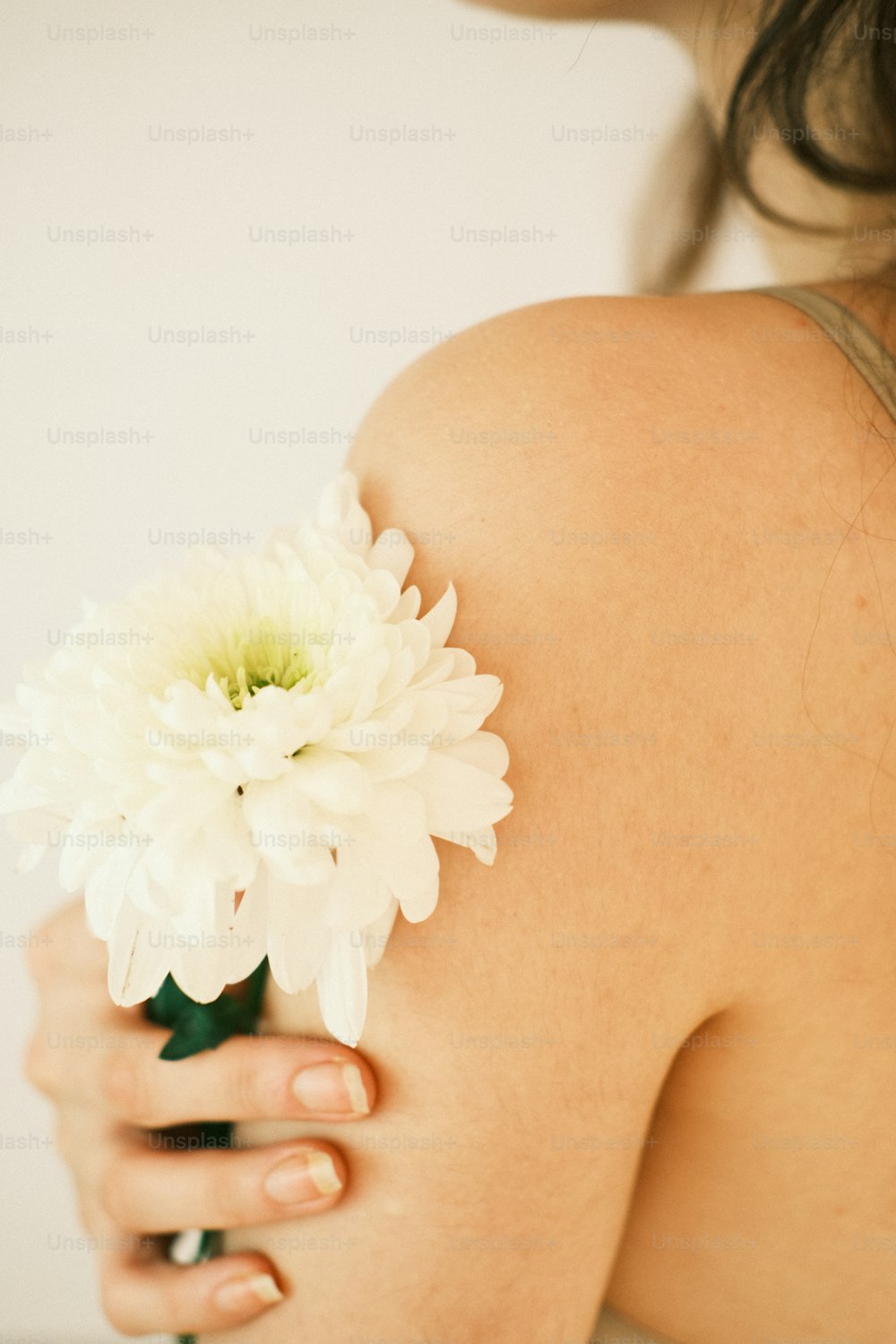 uma mulher segurando uma flor branca em seu braço direito