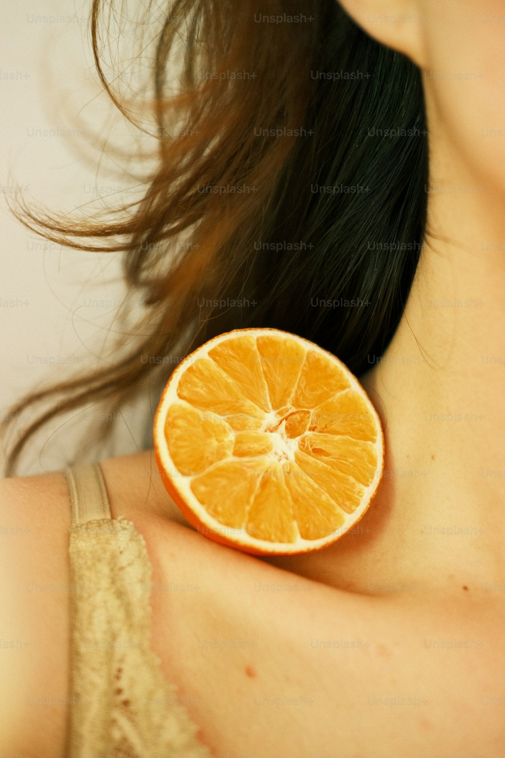 a close up of a woman with a half of an orange on her shoulder