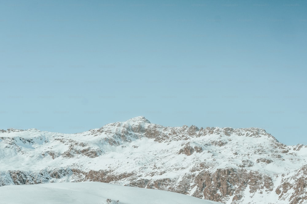 Un hombre montando esquís en la cima de una pendiente cubierta de nieve