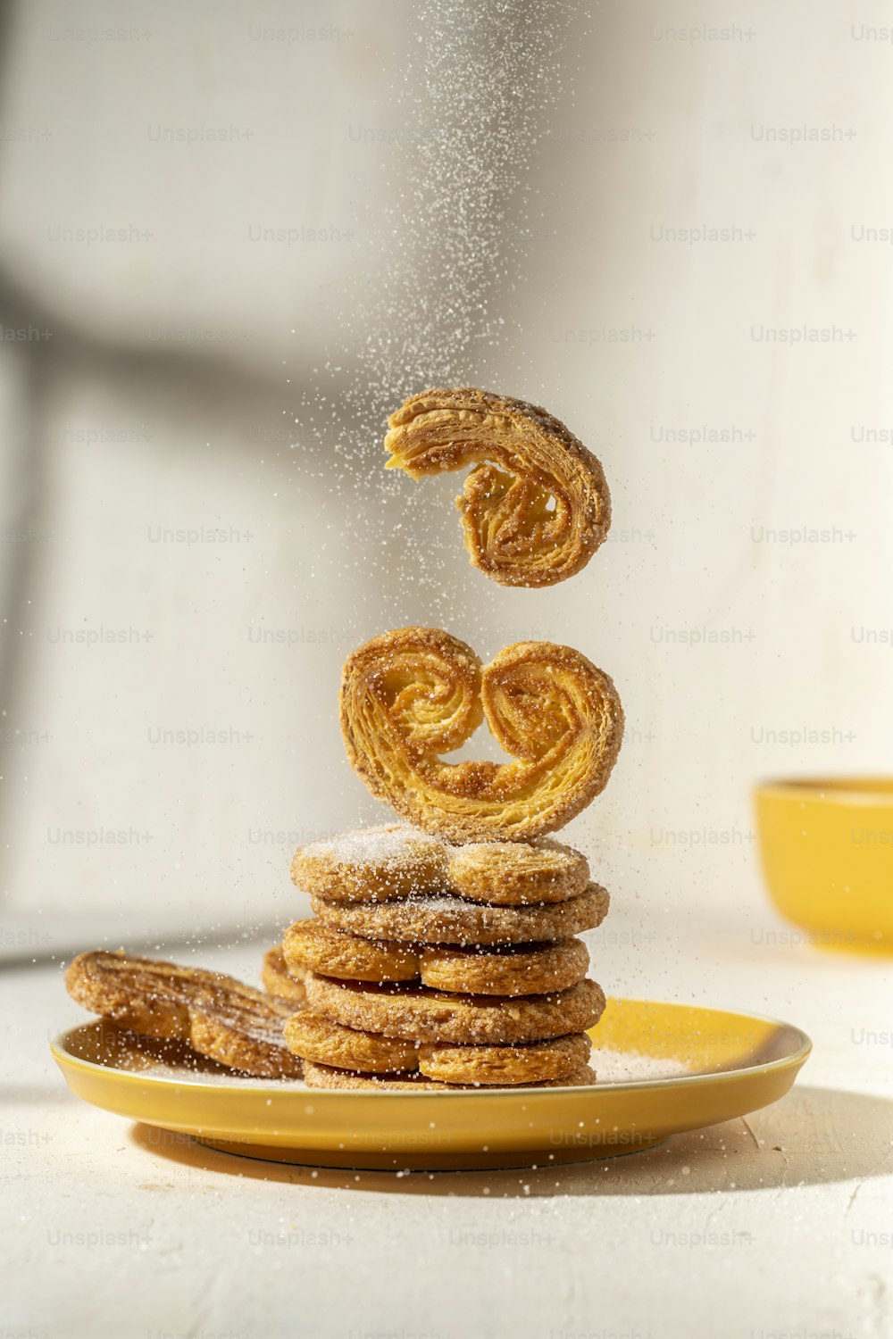 a stack of donuts falling into a yellow plate