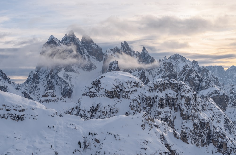 a group of mountains covered in snow under a cloudy sky