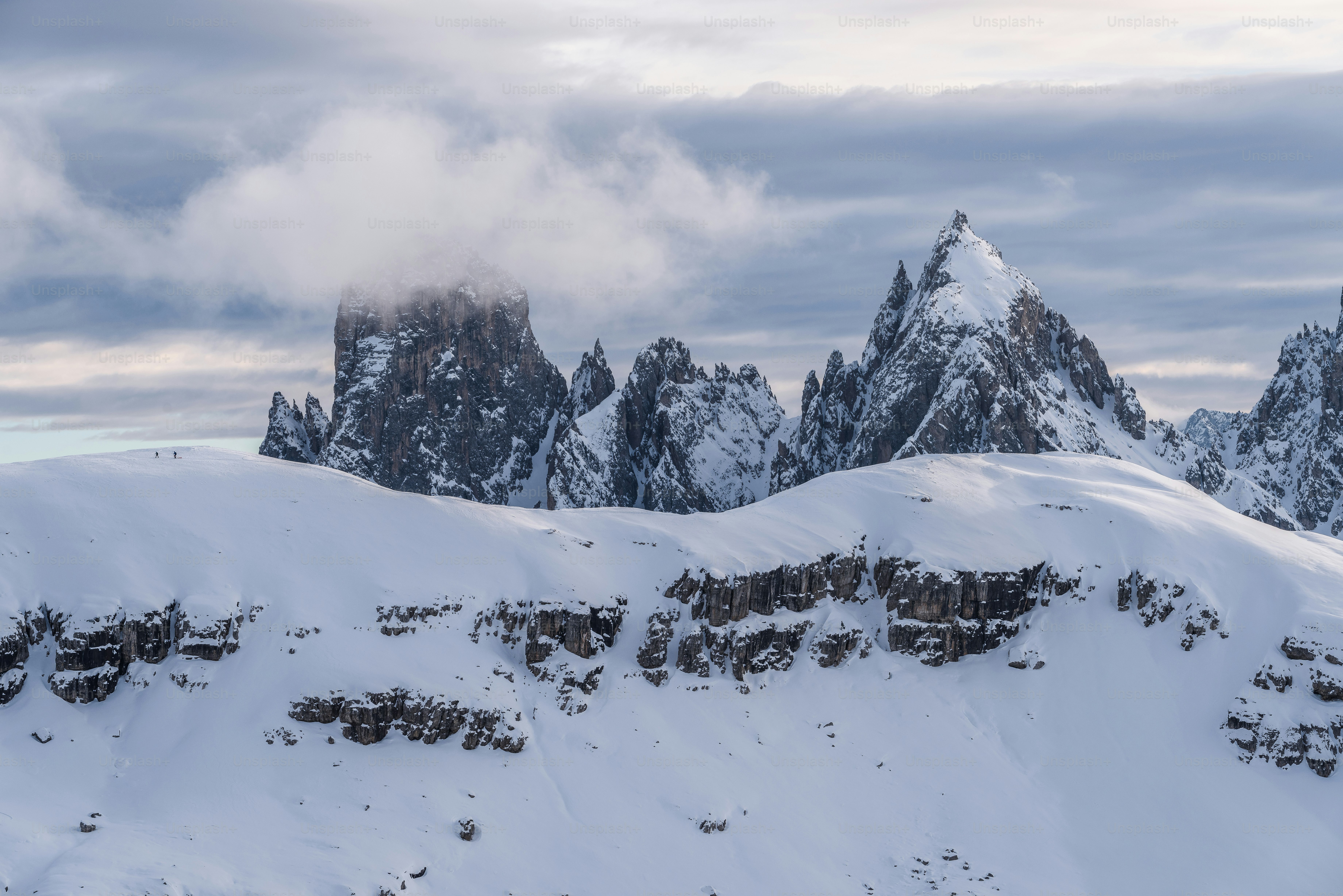 a mountain range covered in snow under a cloudy sky