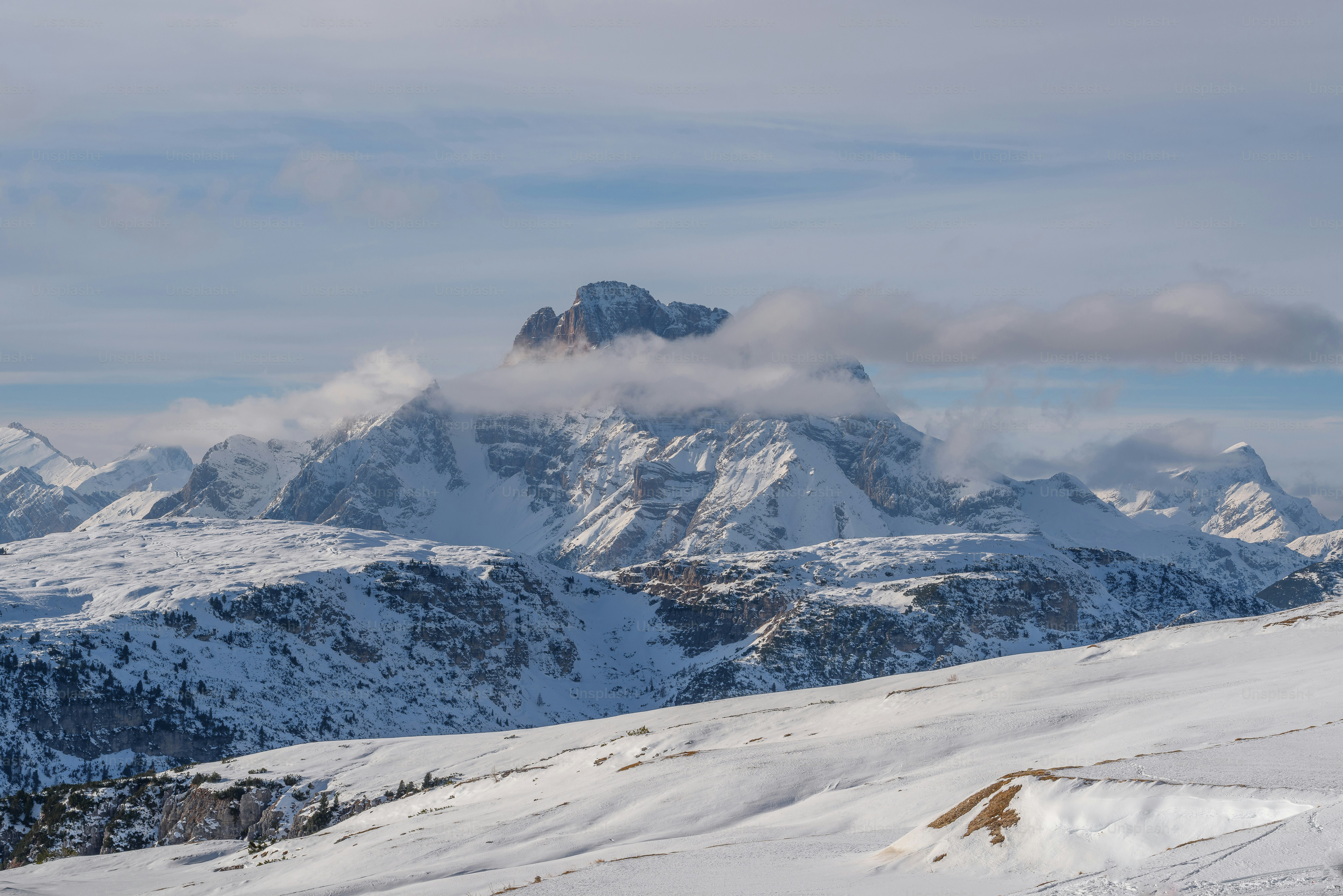 a snow covered mountain range with clouds in the sky