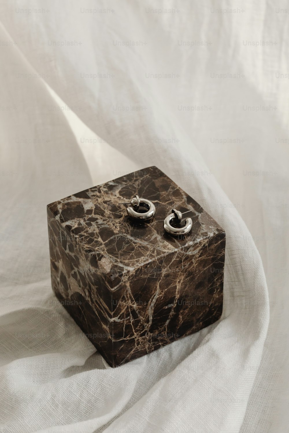 um par de brincos sentados em cima de um bloco de mármore