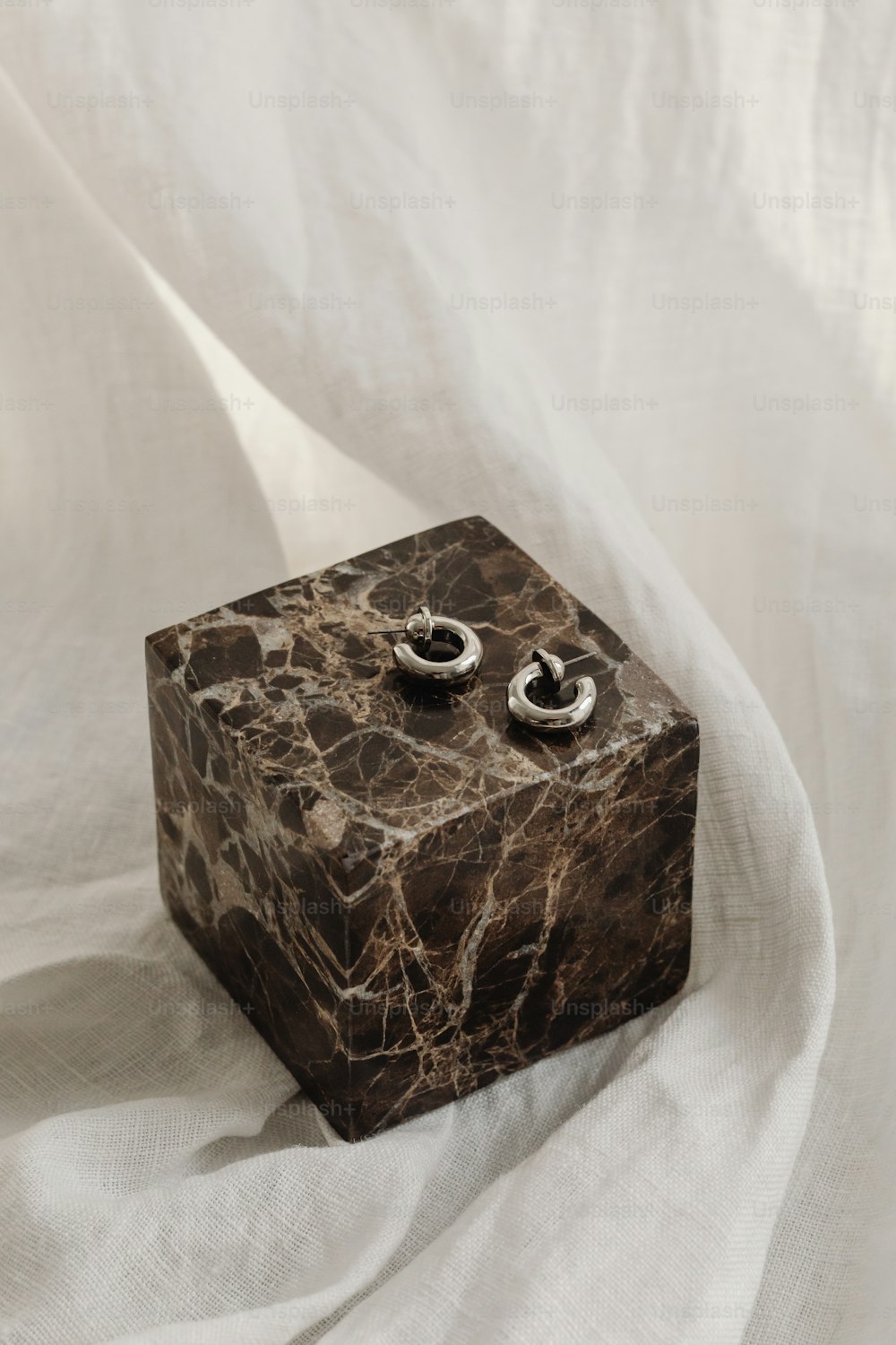 a pair of earrings sitting on top of a marble block
