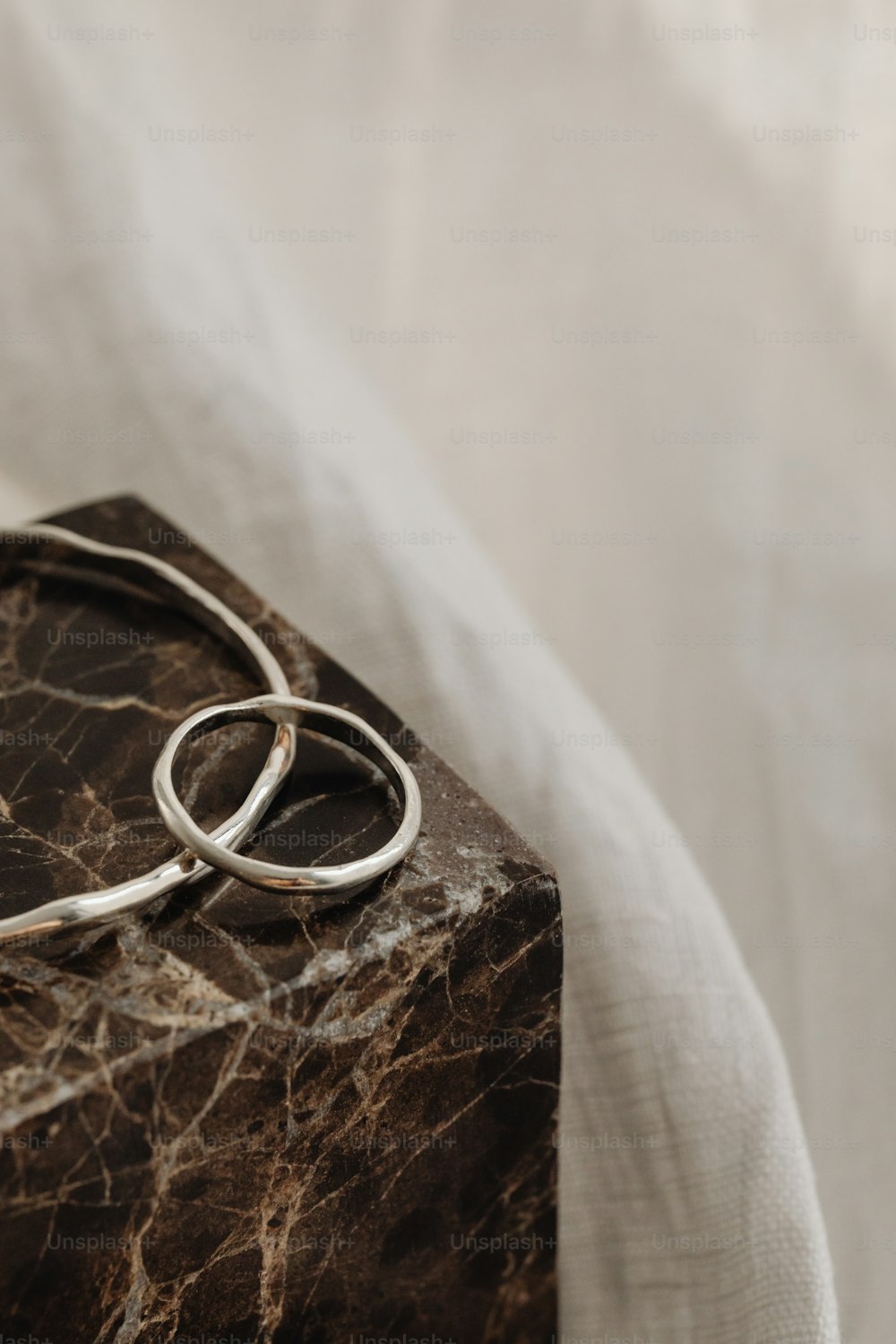 um par de anéis de prata sentados em cima de um bloco de mármore