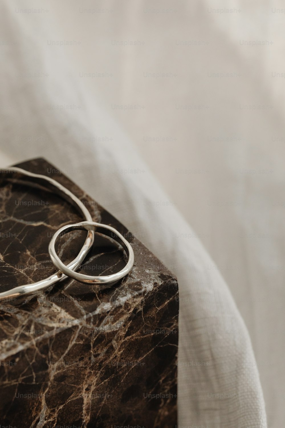 a pair of silver rings sitting on top of a marble block