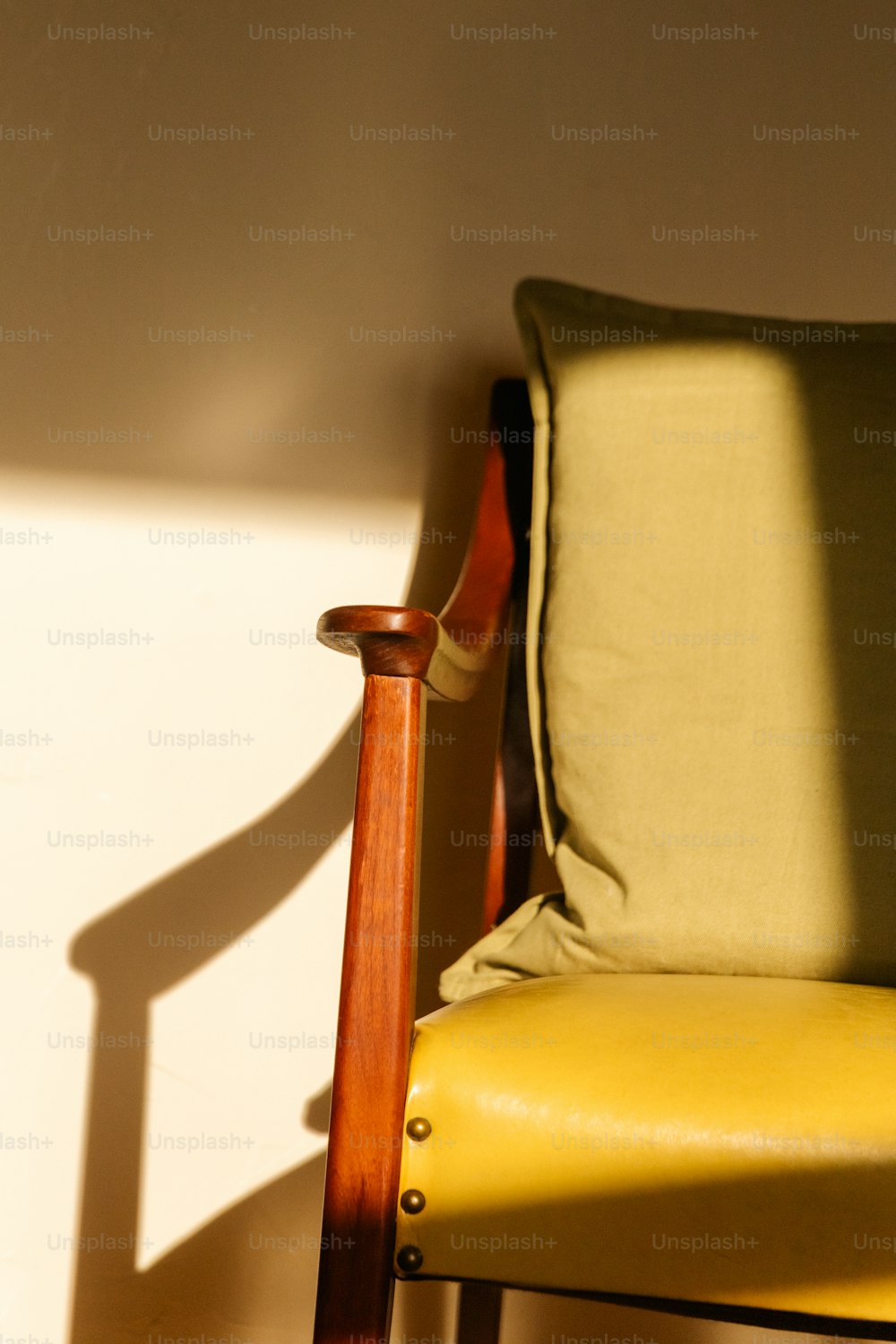 a wooden chair with a yellow seat and a green pillow