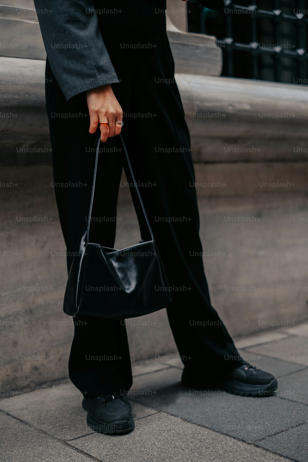 Eine Person, die eine schwarze Handtasche auf einem Bürgersteig hält