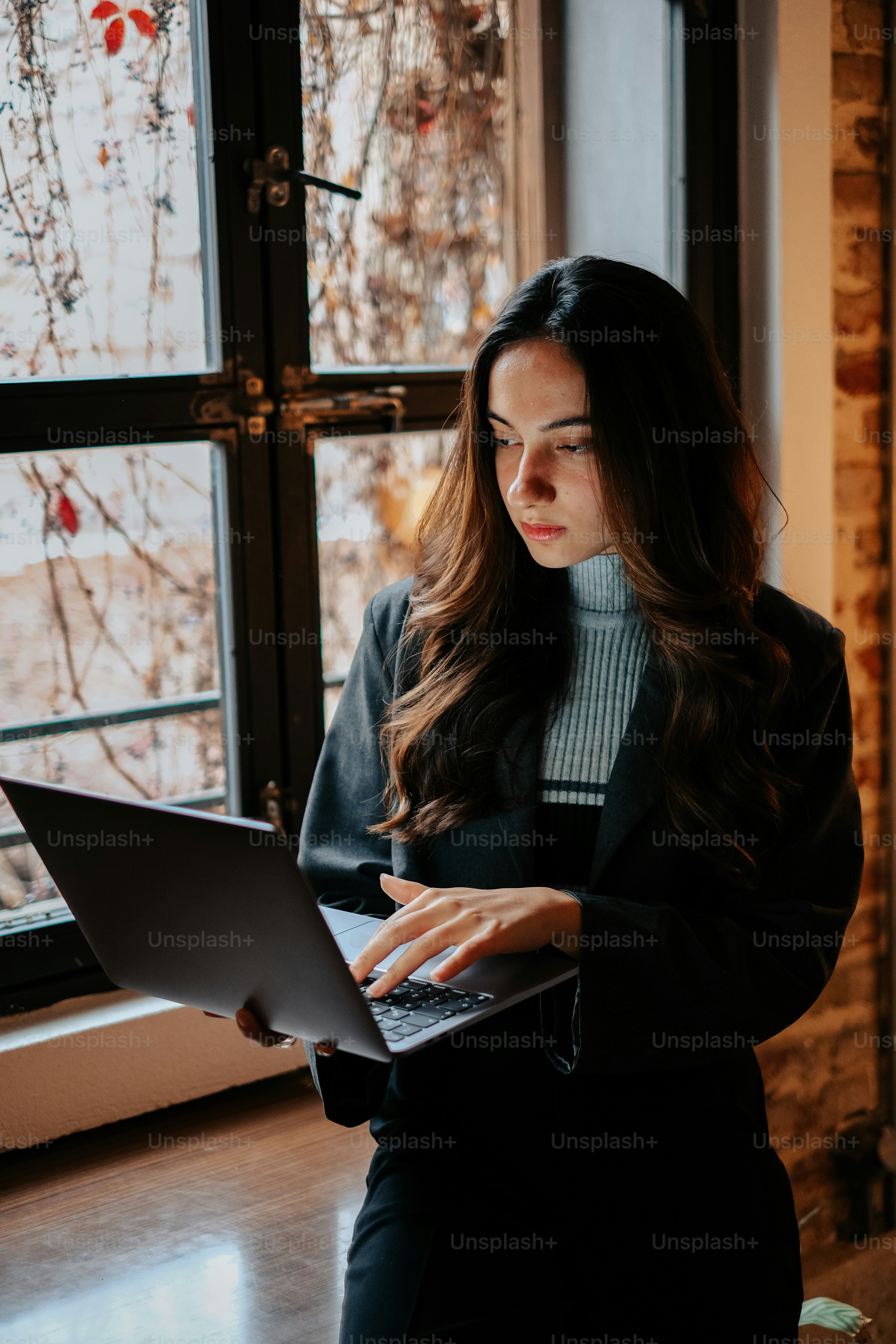 Eine Frau, die mit einem Laptop vor einem Fenster sitzt