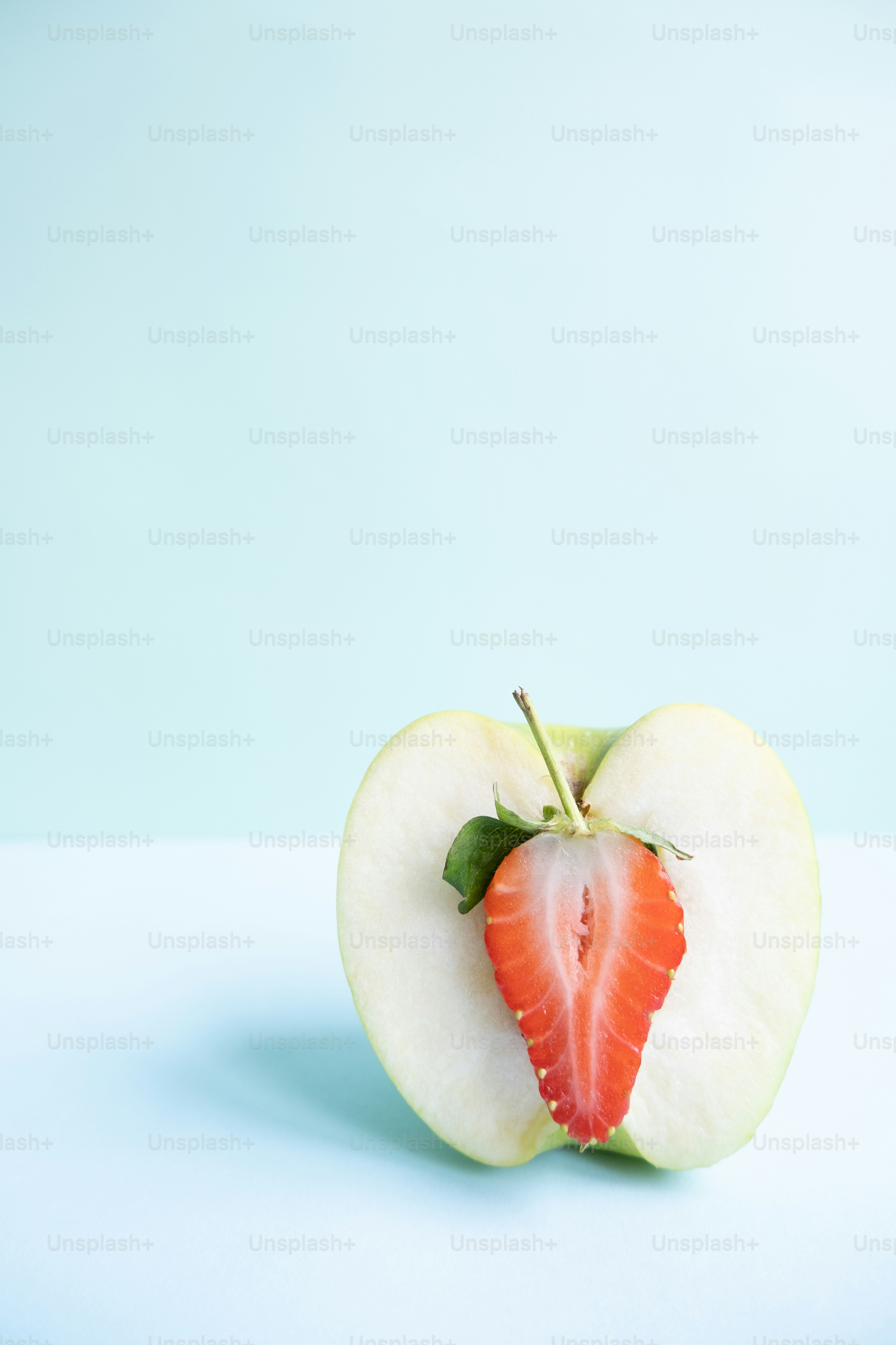 ein halb gegessener Apfel mit einer halbierten Erdbeere