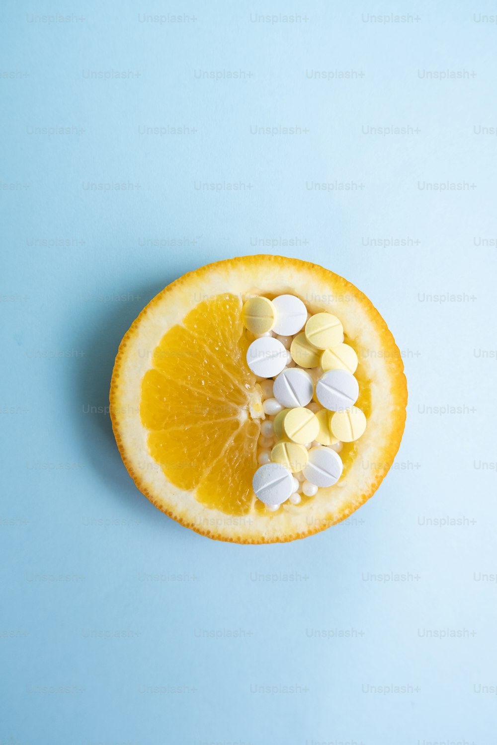 a half of an orange with pills on top of it
