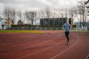 a man running on a track with trees in the background
