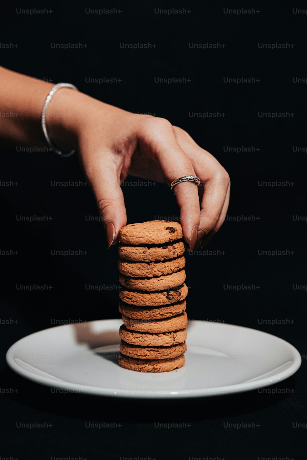 a person stacking a stack of cookies on top of a white plate