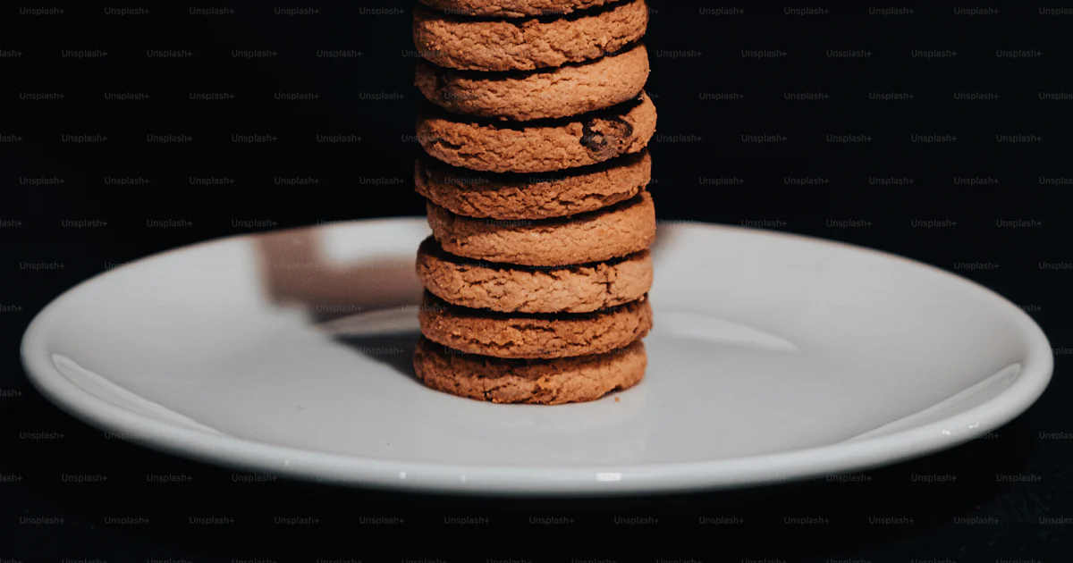 A person stacking a stack of cookies on top of a white plate photo ...