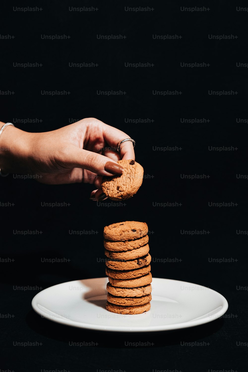 a hand reaching for a cookie on a plate