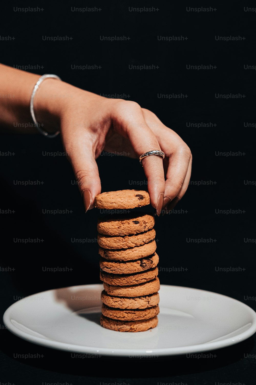 a hand reaching for a stack of cookies on a plate