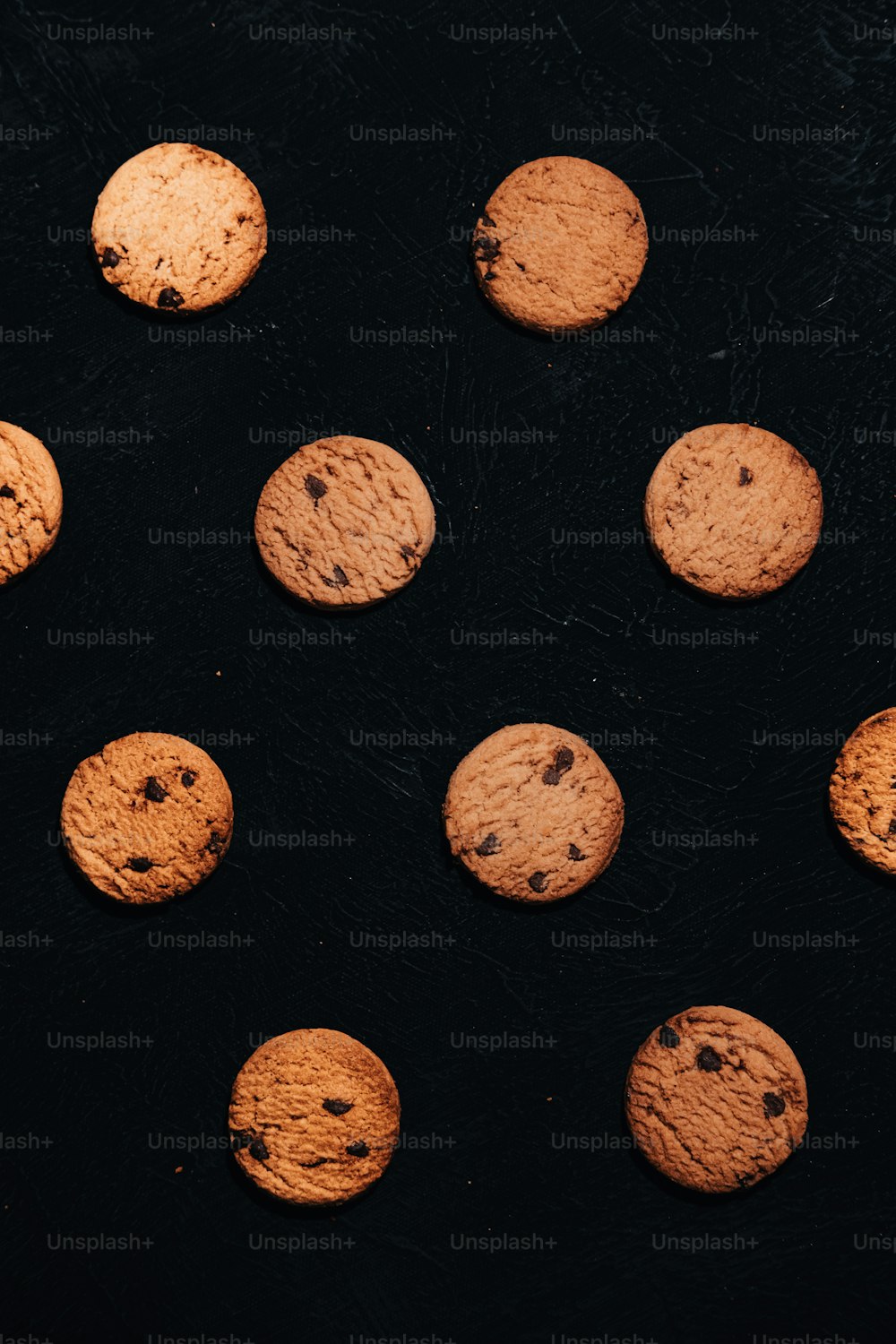 a group of chocolate chip cookies on a black surface