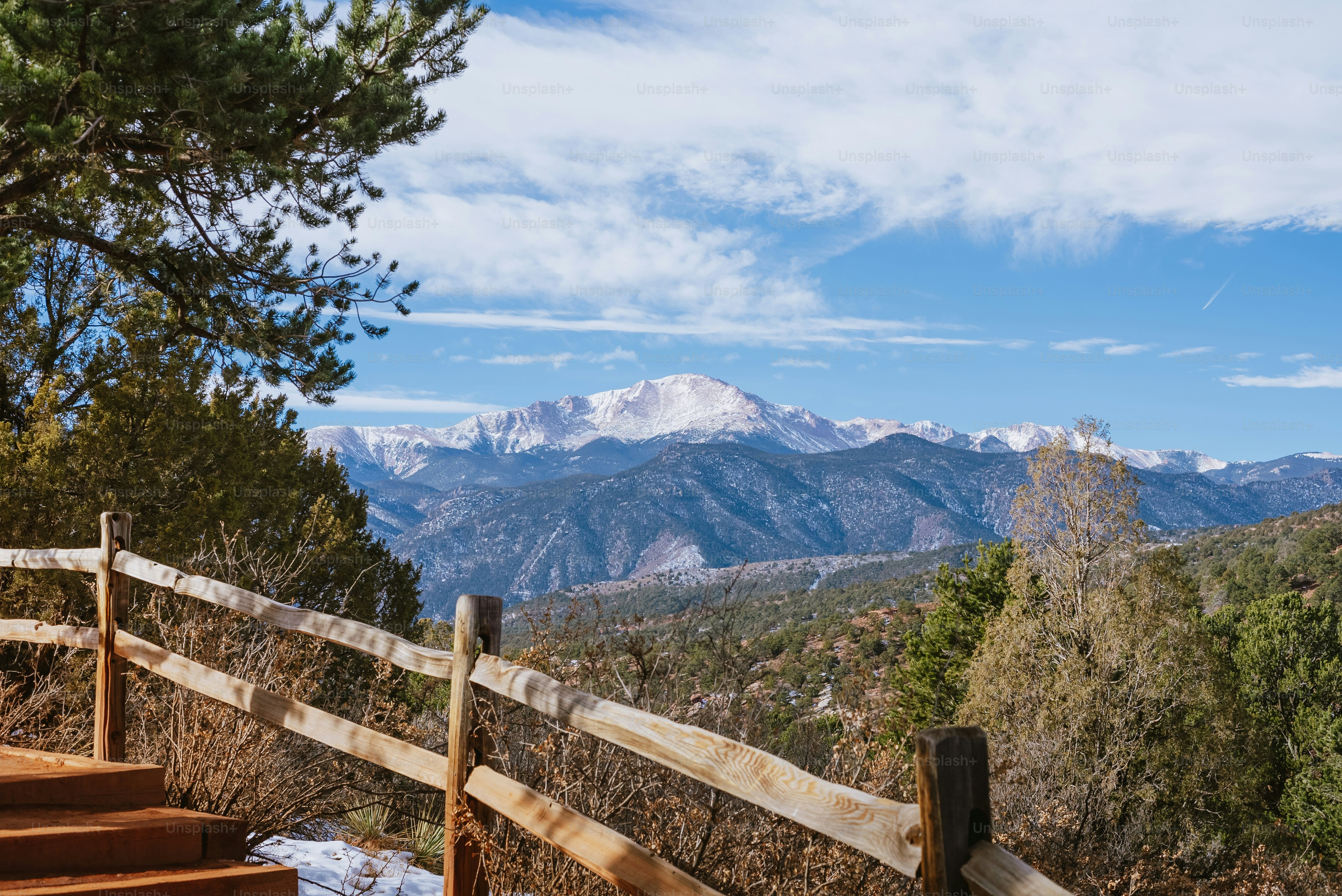 a view of a mountain range from a wooden fence