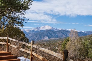 a view of a mountain range from a wooden fence