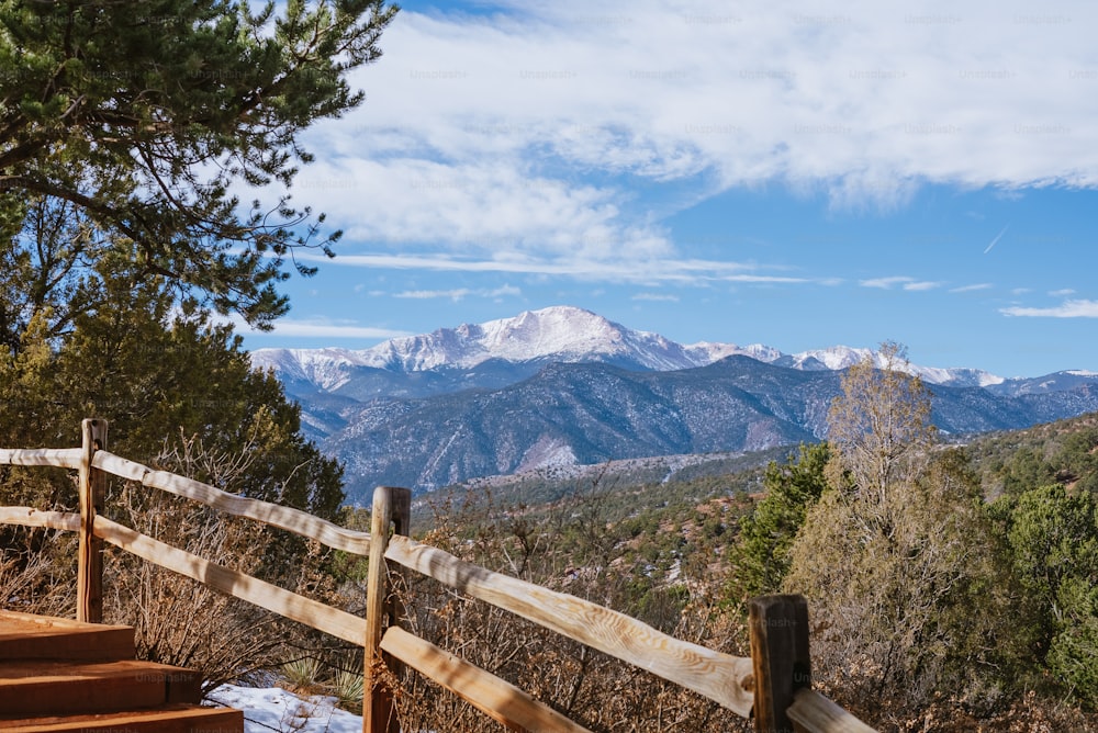 a view of a mountain range from a wooden fence