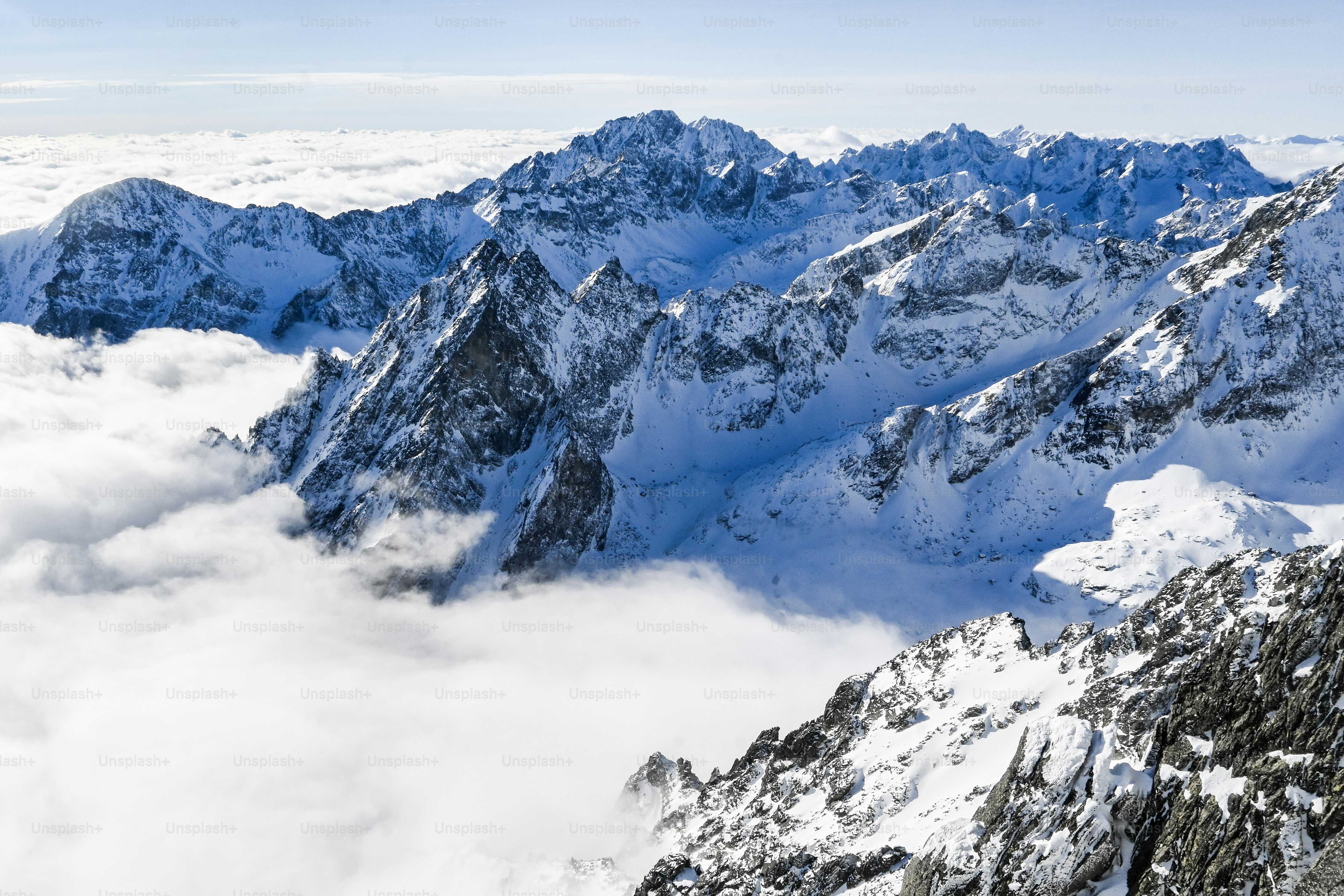 a mountain range covered in snow and clouds