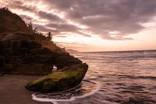 a large rock sitting on top of a beach next to the ocean