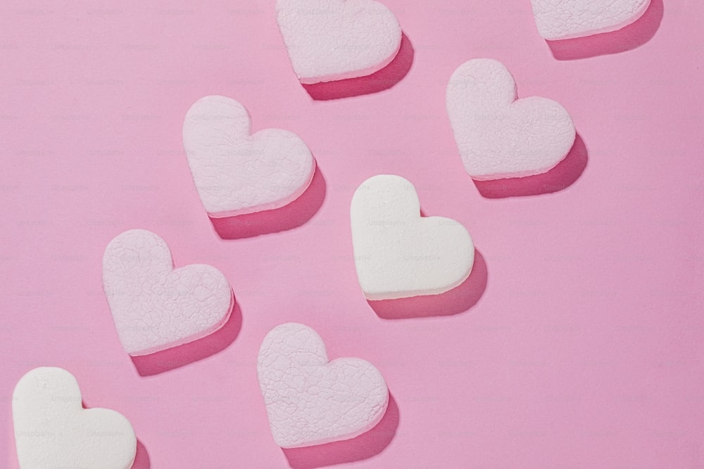 a group of heart shaped marshmallows on a pink background