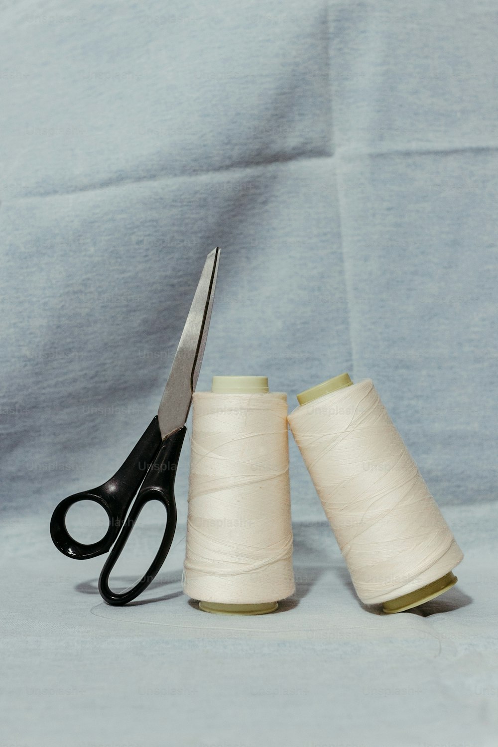 a pair of scissors sitting next to a pair of spools of thread