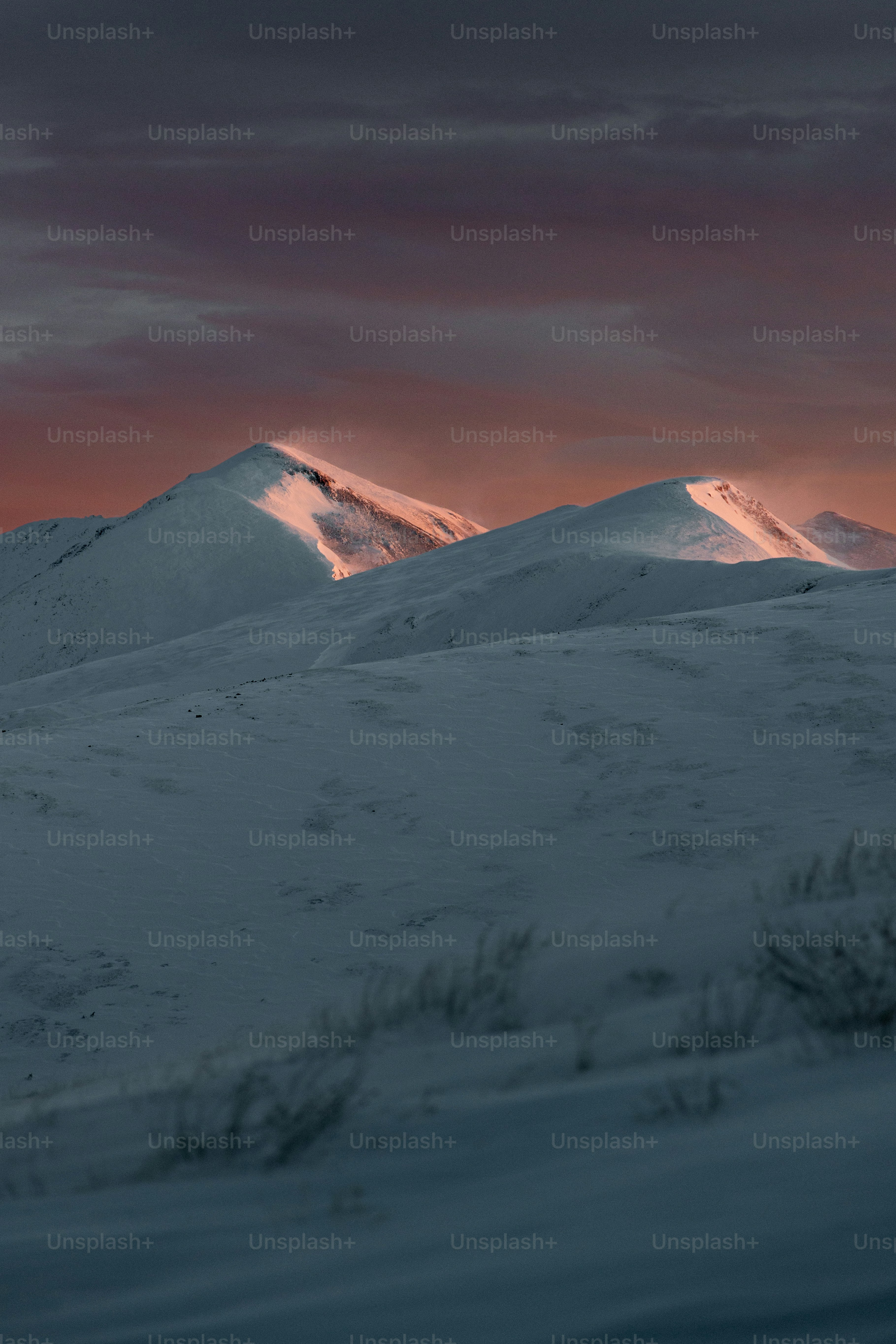 a mountain covered in snow under a cloudy sky