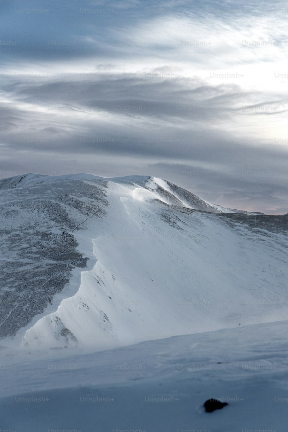 a snow covered mountain under a cloudy sky