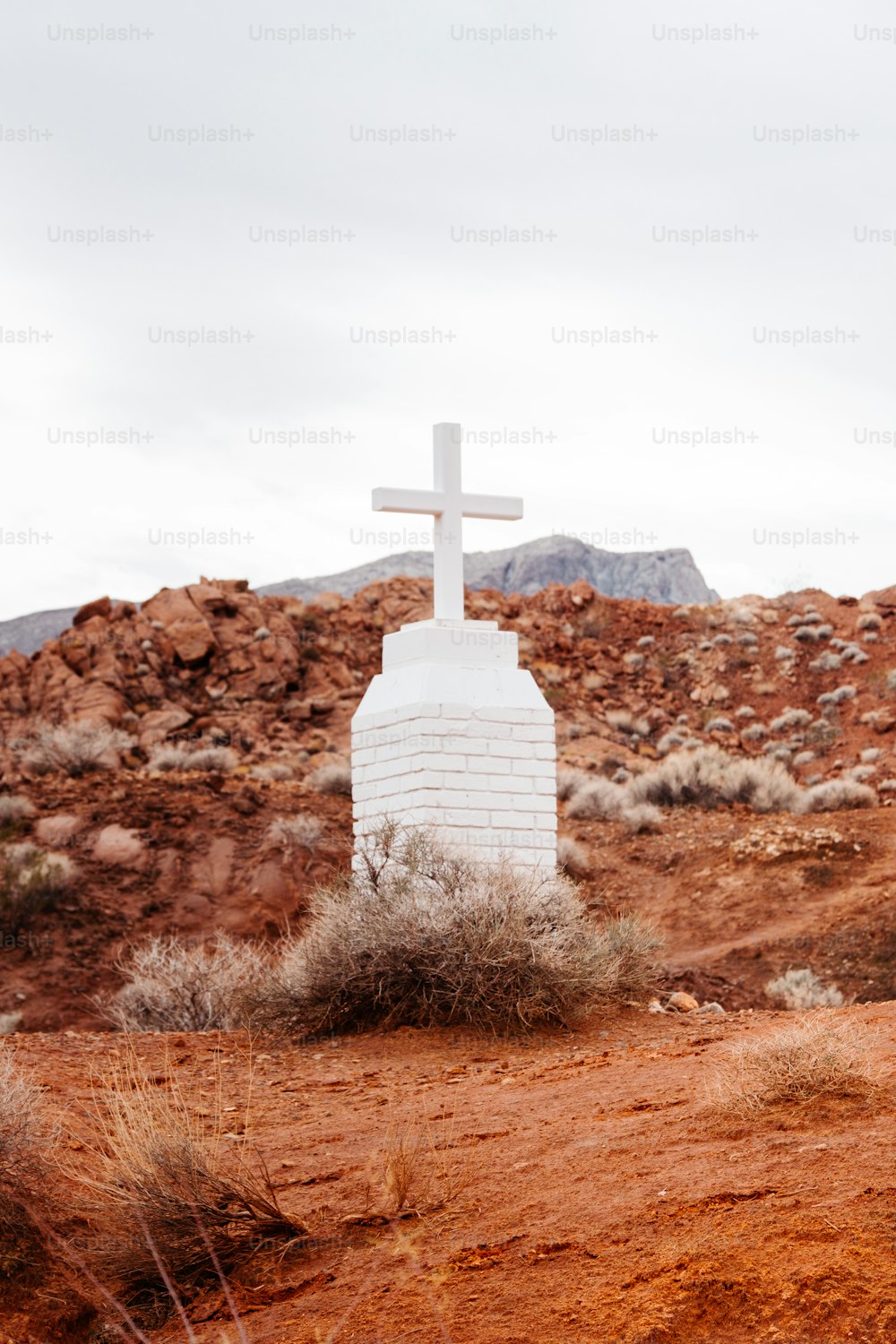 a white cross sitting on top of a dirt field