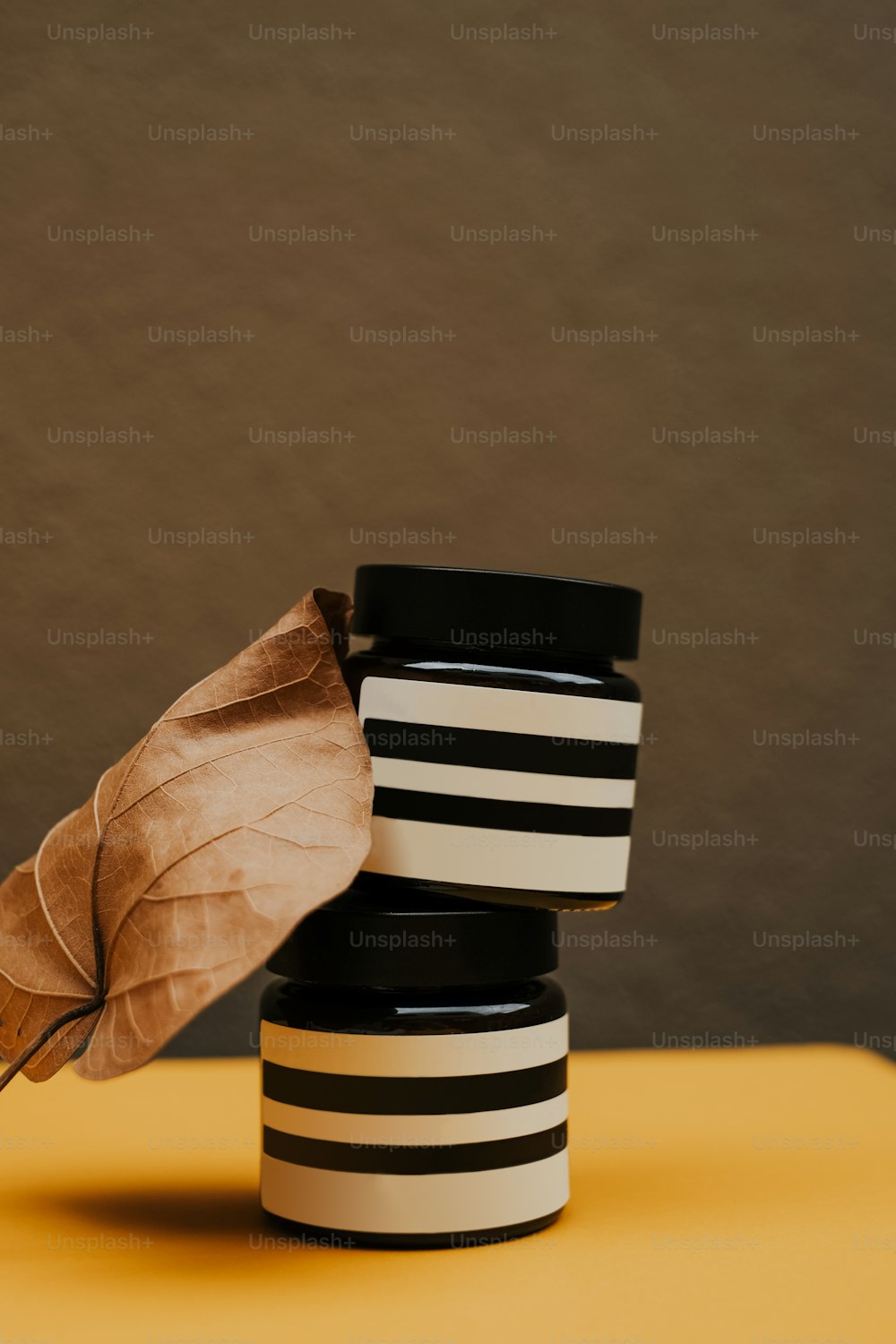 a black and white container with a brown leaf on top of it