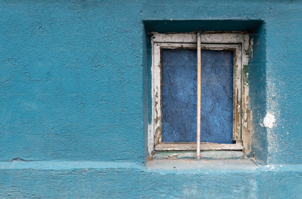 un muro blu con una finestra e un bastone che sporge da esso