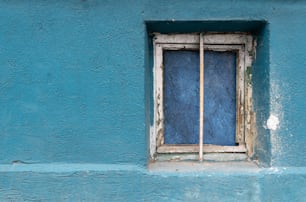 a blue wall with a window and a stick sticking out of it