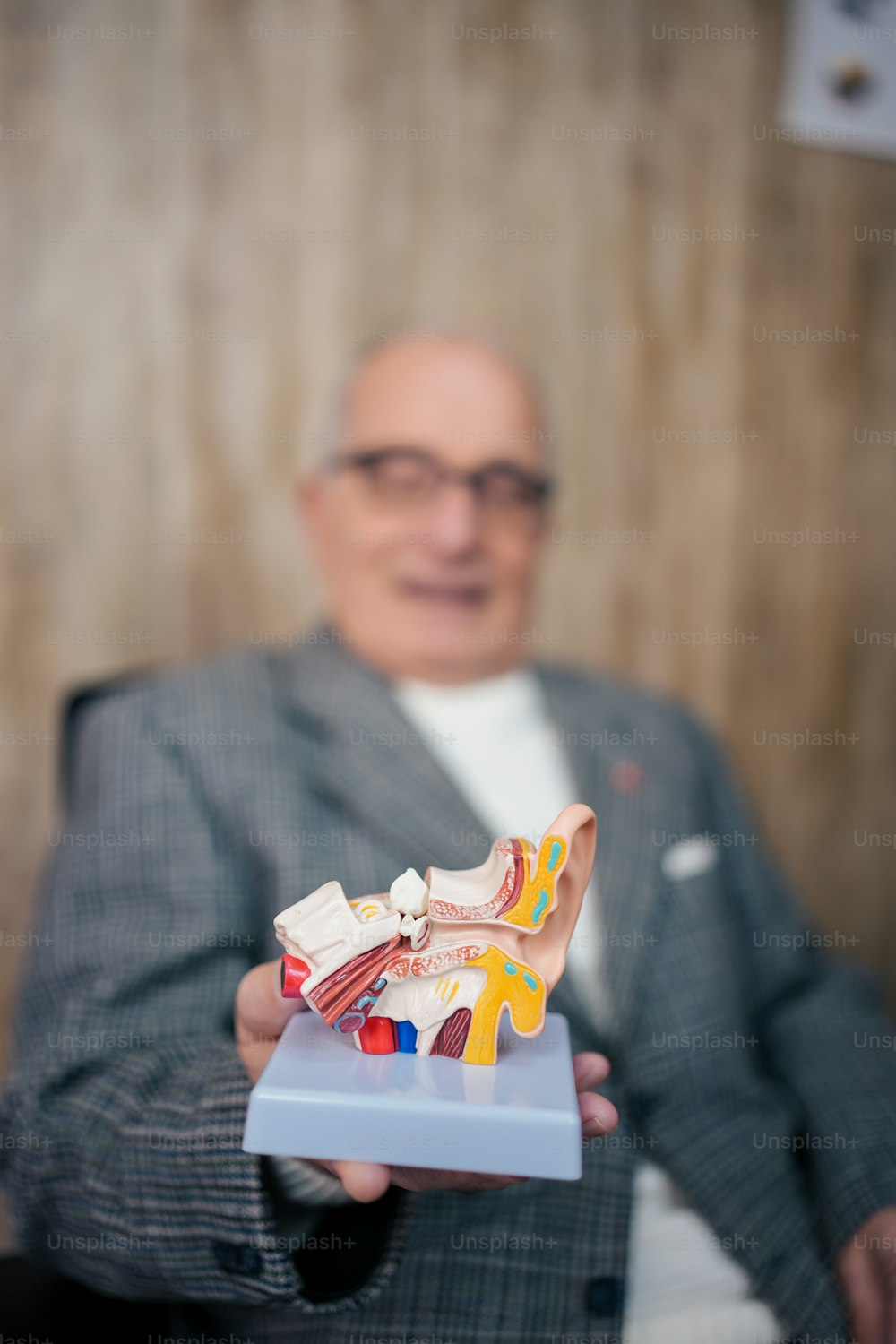 a man in a suit holding a model of a shoe