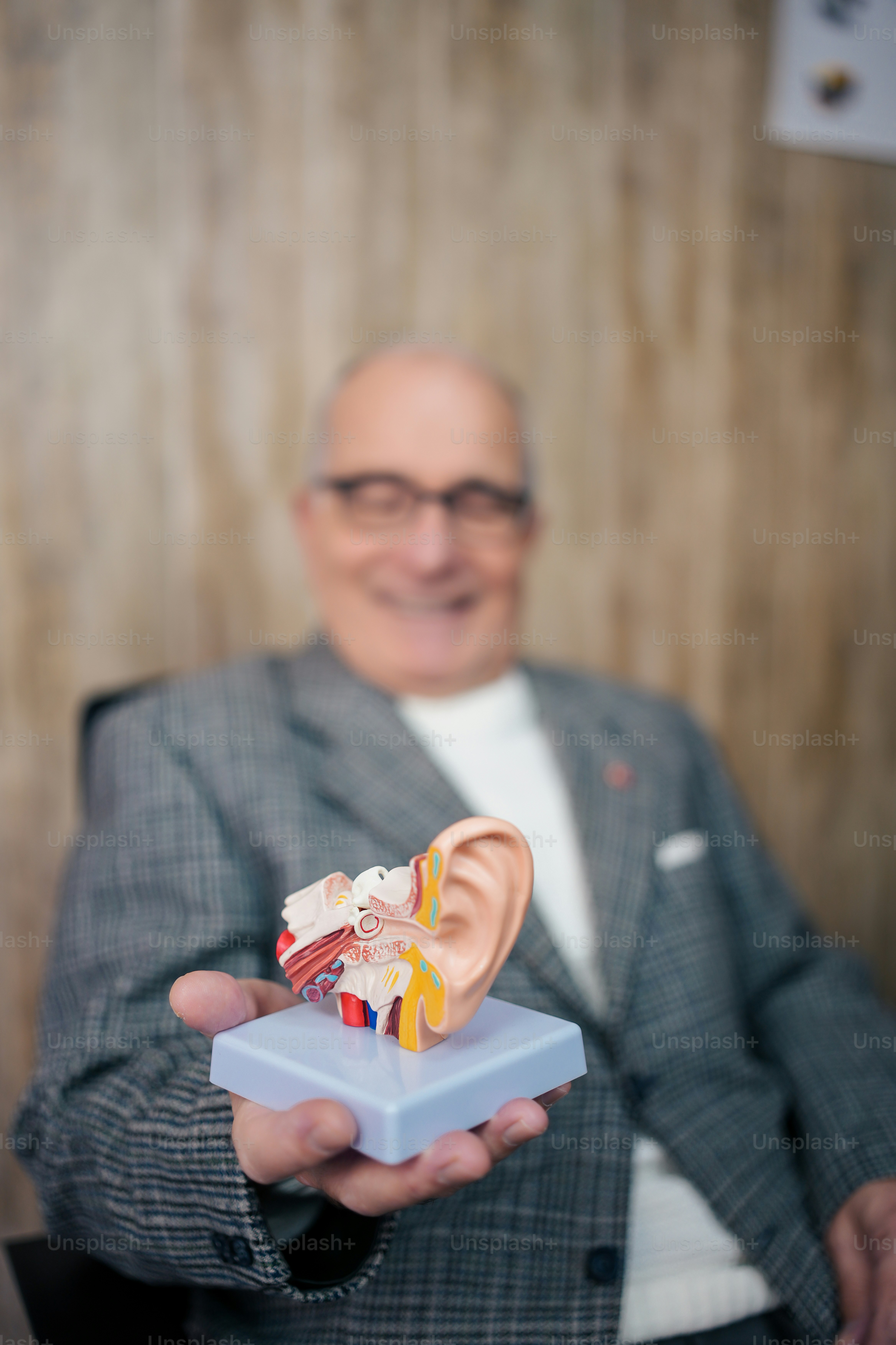 Un hombre con traje sosteniendo una oreja falsa