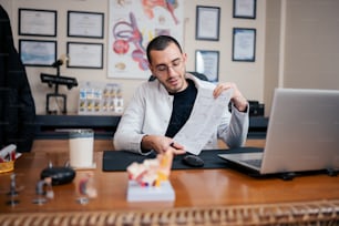 Ein Mann sitzt am Schreibtisch und liest ein Blatt Papier